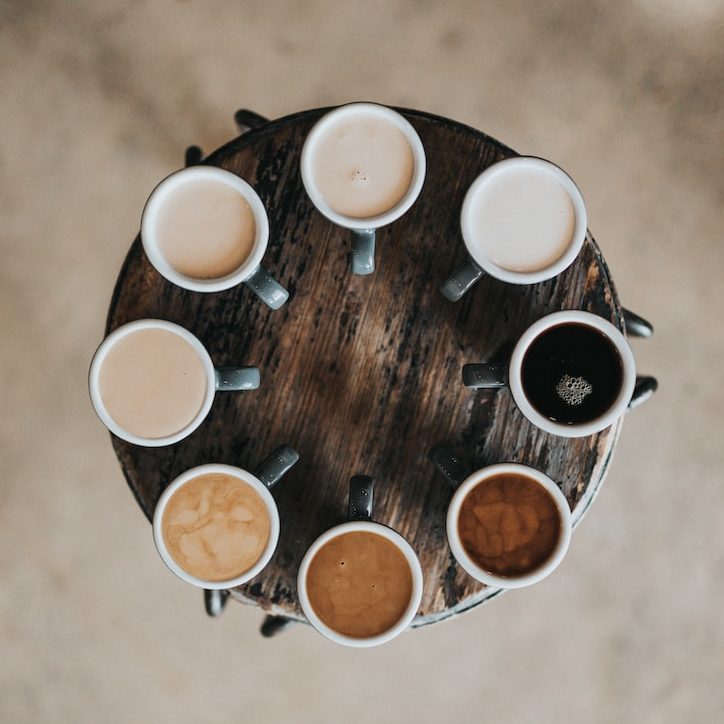 flat lay photography of eight coffee latte in mugs on round table