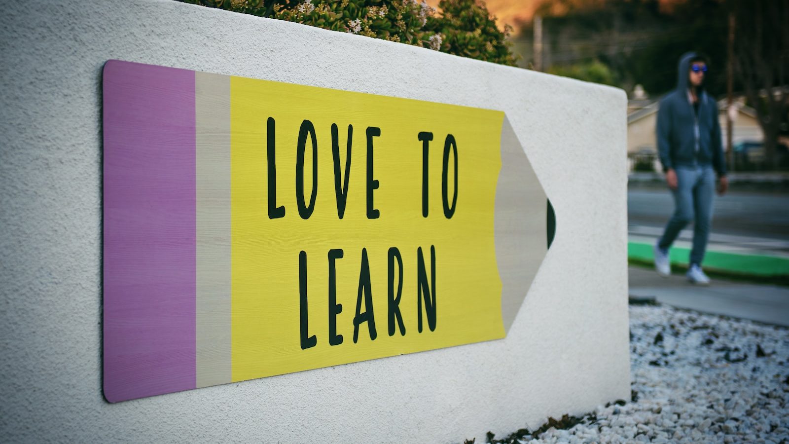 love to learn pencil signage on wall near walking man